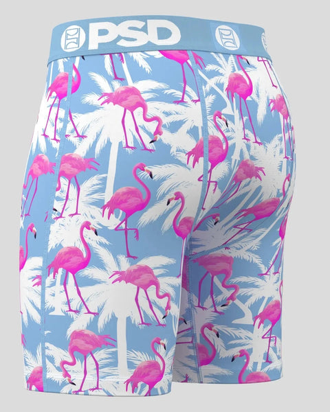 PSD boxer briefs with blue waistband featuring magenta flamingos and white palm fronds on light blue background.