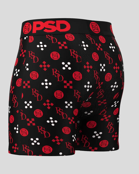 Black boxer shorts with red and white repeating geometric and logo pattern, black waistband with red PSD branding.