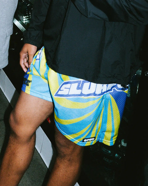 Blue and yellow striped athletic shorts with 7-Eleven Slurpee branding, displayed on model.