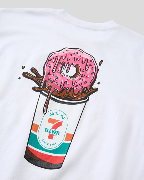 White t-shirt with graphic print of pink frosted donut in 7-Eleven cup with chocolate drizzle.