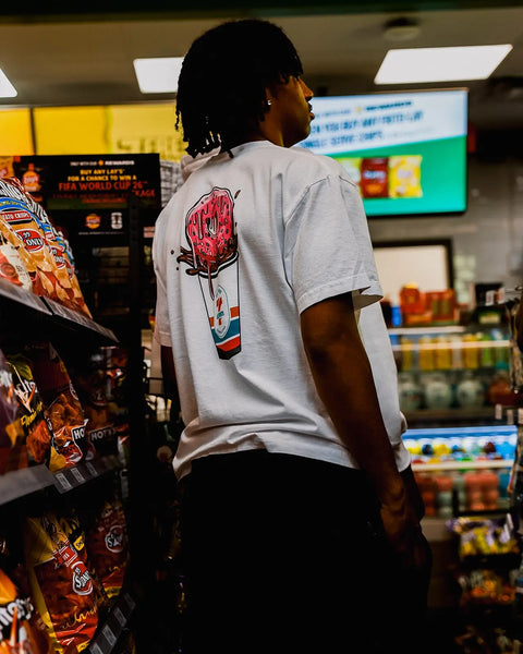 White short-sleeve t-shirt with red donut and 7-Eleven cup graphic on back.